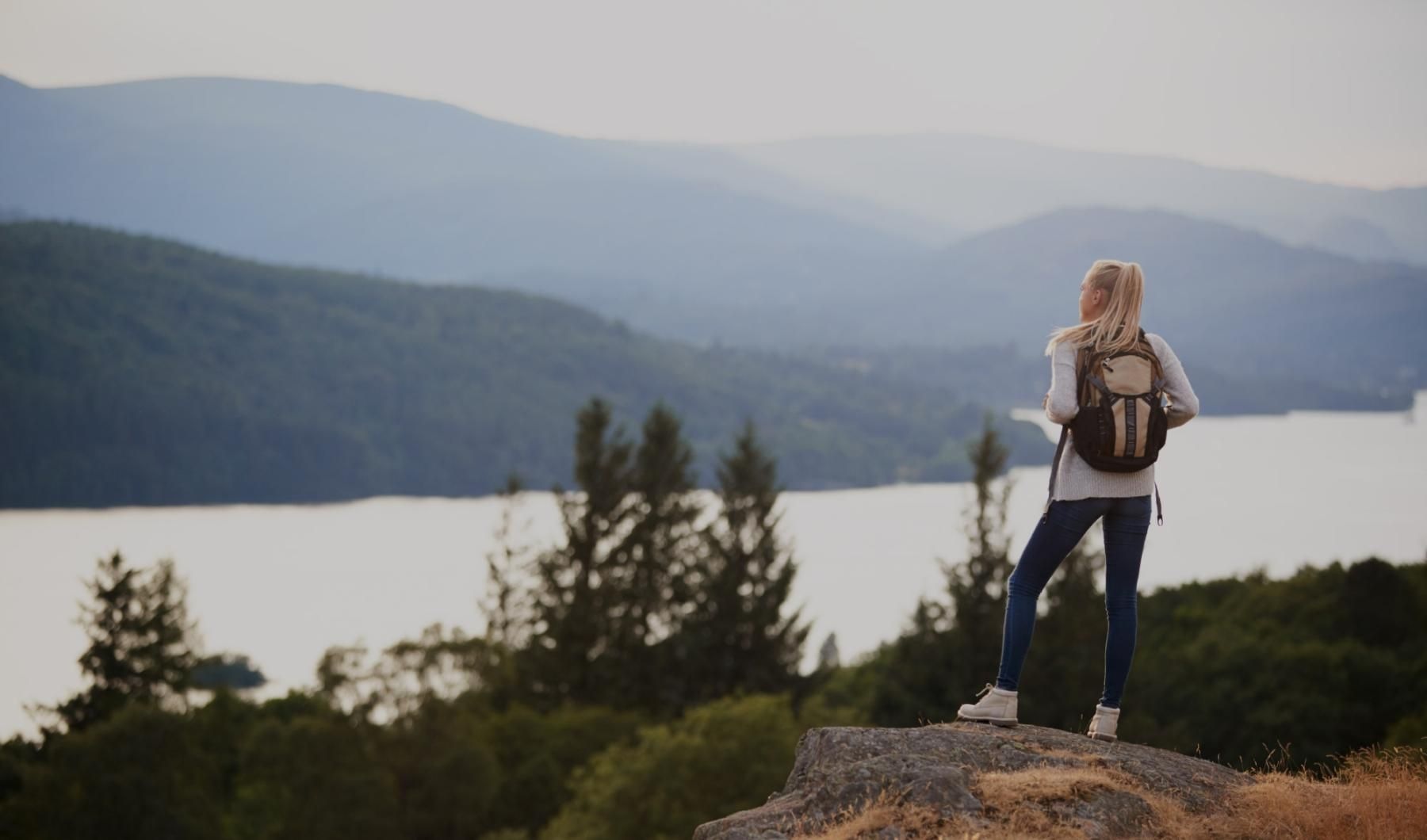 a person standing on a rock overlooking a lake and mountains